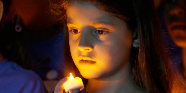 FILE -- April 23, 2014: Melanie Mamondes, 8, participates in a candlelight vigil commemorating National Child Abuse Prevention Month at Jose Marti Park in Miami. Amigos For Kids, a nonprofit organization dedicated to preventing child abuse and neglect, held the event attended by about 200 kids and their families.