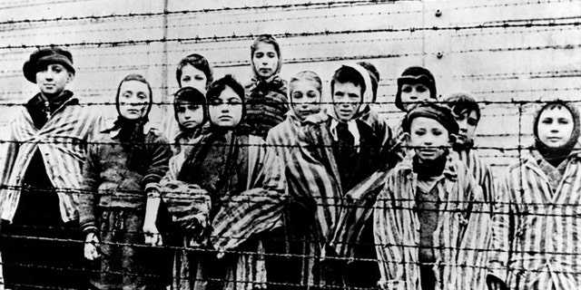 FILE - A picture taken just after the liberation by the Soviet army in January, 1945, shows a group of children wearing concentration camp uniforms behind barbed wire fencing in the Auschwitz Nazi concentration camp. (AP)