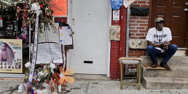FILE: Doug Brinson sits on a stoop next to a makeshift memorial for Eric Garner in Staten Island, N.Y. Garner died after he was put in a chokehold by police officers while being arrested at the site for selling untaxed loose cigarettes. His death has been ruled a homicide.