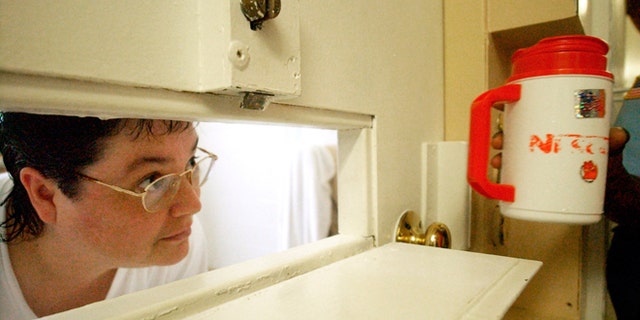 FILE -- July 6, 2004: Kelly Gissendaner, the only woman on Georgia's death row, peers through the slot in her cell door as a guard brings her a cup of ice at Metro State Prison in Atlanta. Gissendaner was convicted of murder in the February 1997 stabbing death of her husband.