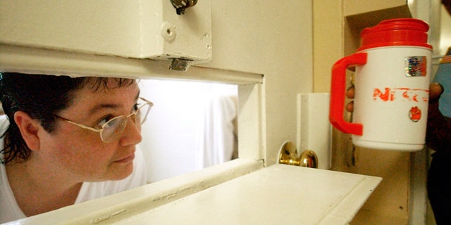 FILE -- July 6, 2004: Kelly Gissendaner, the only woman on Georgia's death row, peers through the slot in her cell door as a guard brings her a cup of ice at Metro State Prison in Atlanta. Gissendaner was convicted of murder in the February 1997 stabbing death of her husband.