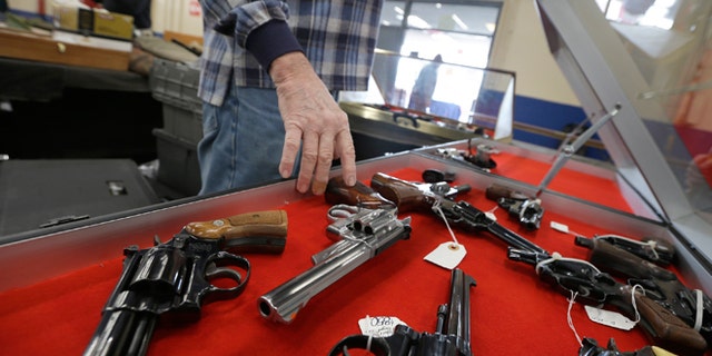 FILE -- Feb. 6, 2015: A dealer arranges handguns in a display case in advance of a show at the Arkansas State Fairgrounds in Little Rock, Ark.