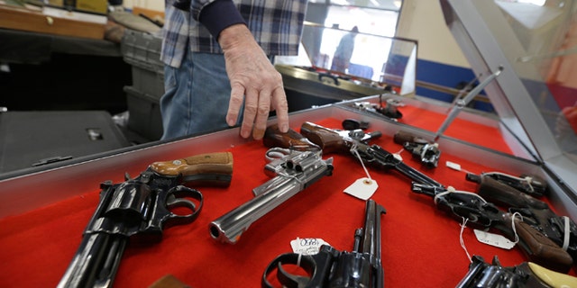 FILE -- Feb. 6, 2015: A dealer arranges handguns in a display case in advance of a show at the Arkansas State Fairgrounds in Little Rock, Ark.