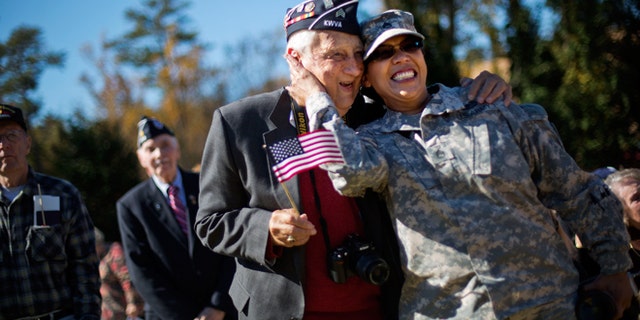 Nov. 11, 2014: U.S. Army Georgia National Guard Staff Sgt. Tracy Smith, right, a veteran of the wars in Iraq and Afghanistan, embraces Korean War veteran Jim Conway, 84, as military service members are asked to sing along to the Armed Services Medley during a Veterans Day ceremony at the Atlanta History Center.