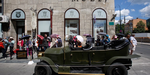Tourists gather on Friday, June 27, 2014, around replica of the "Graf & Stift" car that Archduke Franz Ferdinand and his wife Sofia rode in as it is parked in front of museum at the historical street corner in downtown Sarajevo, where Gavrilo Princip, assassinated Austro-Hungarian heir to the throne Archduke Franz Ferdinand and his wife Sofia, on June 28, 1914. The assassination was the event that ignited the start of World War One.