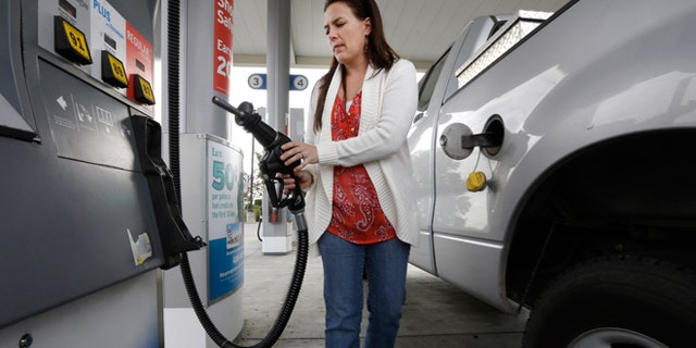 FILE -- Nov. 12, 2014: Lydia Holland replaces the gas nozzle after filling up at a gas station in Sacramento, Calif.