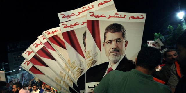 Aug. 6, 2013: A supporter of Egypt's ousted President Mohammed Morsi holds his posters with Arabic writing which reads "Yes for legality"; during a protest outside Rabaah al-Adawiya mosque, where protesters have installed a camp and hold daily rallies at Nasr City in Cairo, Egypt.