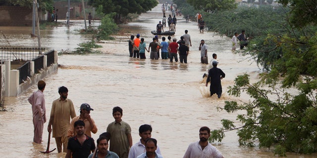 Aug. 4, 2013: People wade through flooded road caused by heavy rains on the outskirts of Karachi, Pakistan.