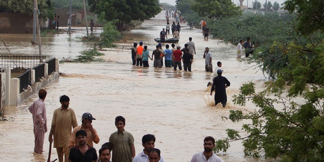 Aug. 4, 2013: People wade through flooded road caused by heavy rains on the outskirts of Karachi, Pakistan.