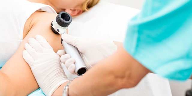 Woman undergoing medical exam using dermoscope, copy space