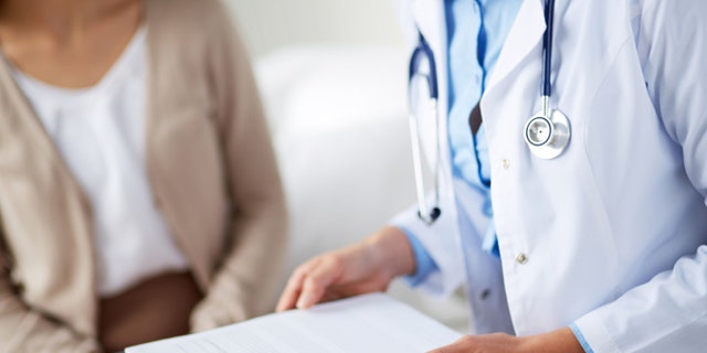 Female doctor holding application form while consulting patient
