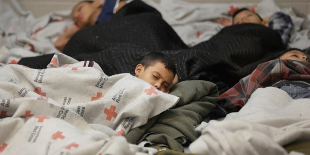 Detainees sleep in a holding cell at a U.S. Customs and Border Protection processing facility, in Brownsville, Texas June 18, 2014. CPB provided media tours June 18 of two locations in Brownsville and Nogales, Arizona that have been central to processing the more than 47,000 unaccompanied children who have entered the country illegally since Oct. 1. REUTERS/Eric Gay/Pool (UNITED STATES - Tags: CRIME LAW POLITICS SOCIETY) - RTR3UI3Q