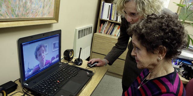 Tamara Rusoff-Hoen, right, watches a video she recorded for her mother, Louise Irving, with Charlotte Dell, Director of Social Services at The Hebrew Home of Riverdale, in New York, Wednesday, March 25, 2015. The nursing home in the Bronx has started a pilot program in which relatives record video messages for patients of Alzheimer's and other forms of dementia. The videos are played for them each morning to calm their agitation and reassure them about their surroundings and their routines.