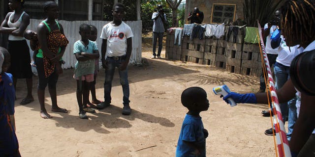 Health workers take the temperature of a boy who came in contact with a woman who died of Ebola virus in the Paynesville neighborhood of Monrovia, Liberia, January 21, 2015.