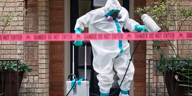 A member of the CG Environmental HazMat team disinfects the entrance to the residence of the first health worker at the Texas Health Presbyterian Hospital to contract Ebola in Dallas, Texas, October 12, 2014.