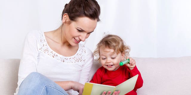 A mom is shown reading a book to her child. Some libraries are reducing their days or hours of operation due to the current omicron surge — while others are closing completely or offering "curbside" pickup services.