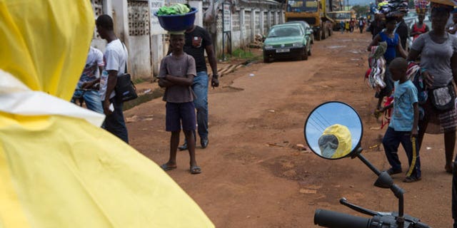 A health worker is reflected in a mirror as he prepares protective equipment near Rokupa Hospital, Freetown October 6, 2014.