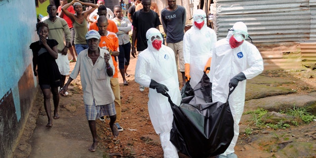 Health workers remove the body of Prince Nyentee, a 29-year-old man whom local residents said died of Ebola virus in Monrovia September 11, 2014. REUTERS/James Giahyue (LIBERIA - Tags: DISASTER HEALTH TPX IMAGES OF THE DAY) - RTR45VJ6