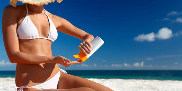 Woman taking out sunscreen at the beach