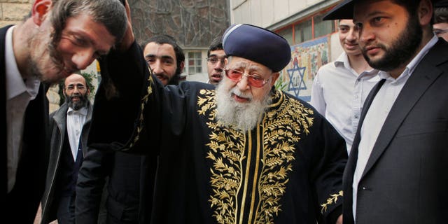 FILE - In this Feb. 10, 2009 file photo, Rabbi Ovadia Yosef, center, Jewish spiritual leader of Israel's Shas party, blesses a man after casting his ballot at a polling station in Jerusalem. An Israeli health official said Saturday Jan. 12, 2013, that influential Yosef has been hospitalized after feeling unwell. (AP Photo/Kevin Frayer, File)