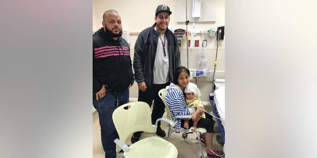 In this Oct. 14, 2016 photo released by the New York City Police Department, officers Felix Baez, left, and Giovanni Laguna pose for a photo with Liliana Benigno, and her one-year-old baby Ashley Delores, at Lincoln Hospital in The Bronx borough of New York. The officers were on patrol Friday night when they saw the Benigno running with her child down the street yelling "help" in Spanish. Seeing that the child was unresponsive, Laguna placed the baby on the ground and began CPR while Baez called for an ambulance. Police say after a minute of CPR, the baby's eyes opened and Laguna felt a faint pulse. (New York City Police Department via AP)