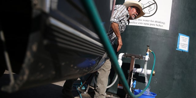 PORTERVILLE, CA - SEPTEMBER 04: Mario Garcia fills buckets with non-potable water from a tank set up in front of the Doyle Colony Fire Station on September 4, 2014 in Porterville, California. More than 300 homes in the California central valley city of Porterville have been without running water for weeks after their wells ran dry due to the severe drought. County officials and charitable organizations are providing drinking water and non-potable water for use in washing dishes and bathing. (Photo by Justin Sullivan/Getty Images)