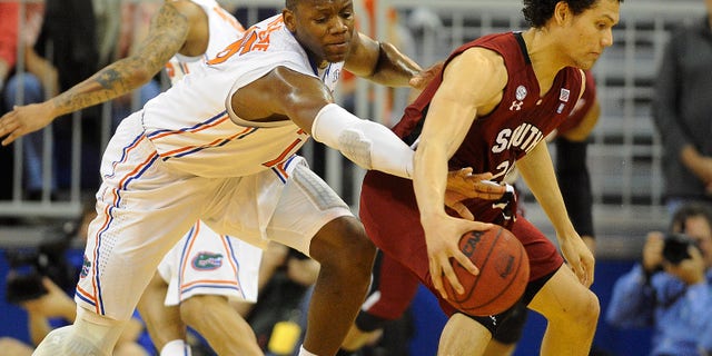 Florida forward Will Yeguete (15) tries to knock the ball out of the hands of South Carolina's Michael Carrera (24) during the first half of an NCAA college basketball game in Gainesville, Fla., Wednesday, Jan. 30, 2013. (AP Photo/Phil Sandlin)