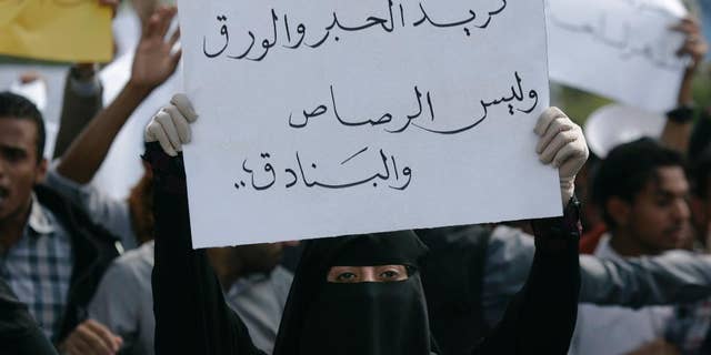A student holds a banner with Arabic that reads, "we want ink and pens not bullets and rifles," to protest against the Shiite insurgency during a rally at the University of Sanaa, Yemen, Tuesday, Nov. 25, 2014. (AP Photo/Hani Mohammed)
