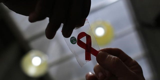 Nurse gives a red ribbon to a woman to mark World Aids Day at the entrance of Emilio Ribas Hospital, in Sao Paulo
