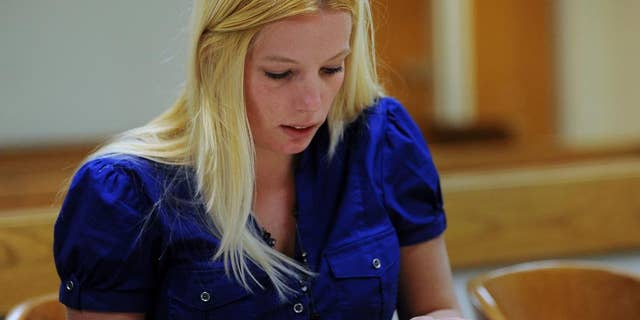 In this April 5, 2012, photo,Teana Walsh, assistant prosecutorfor Wayne County, goes over evidence during a hearing in 36th District Court in Detroit. Walsh, who quit last year after posting on Facebook that people assaulting police officers in Baltimore should be shot, has returned to work for her former employer. Wayne County prosecutor's office spokeswoman Maria Miller said in an email Thursday, July 14, 2016, that Walsh returned to work as a part-time contract employee in June. (Charles V. Tines/Detroit News via AP)