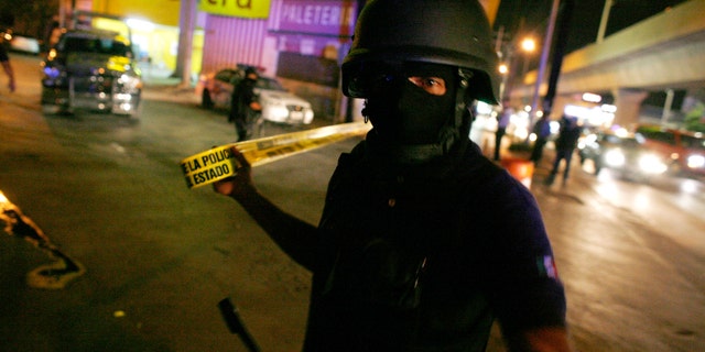File photo. June 11, 2010: A Mexican policeman cordons off a crime scene.