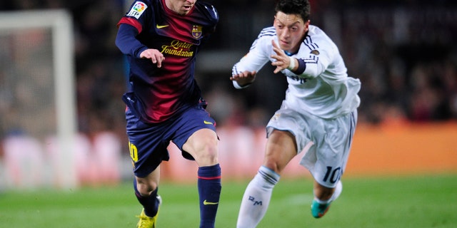 Barcelona's Lionel Messi from Argentina, left, and Real's Mesut Ozil from Germany challenge for the ball during a Copa del Rey soccer match between FC Barcelona and Real Madrid at the Camp Nou stadium in Barcelona, Spain, Tuesday, Feb. 26, 2013. (AP Photo/Manu Fernandez)