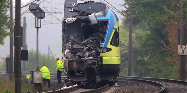 Workers are busy near the damaged train that hit a truck on a road crossing near Ibbenbueren, western Germany, Saturday, May 16, 2015. Police said two people have been killed and at least 20 others were injured in the accident. (Marcel Kusch/dpa via AP)