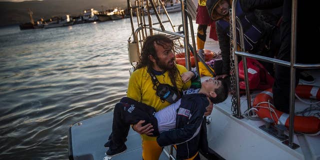 A volunteer carries a young boy after a boat with refugees and migrants sank while crossing the Aegean sea from Turkey to the Greek island of Lesbos, on Wednesday, Oct. 28, 2015.  The condition of the child is not known. The Greek coast guard said it rescued 242 refugees or economic migrants off the eastern island of Lesbos Wednesday after the wooden boat they traveled in capsized, leaving at least three dead on a day when another 8 people drowned trying to reach Greece. (AP Photo/Santi Palacios)