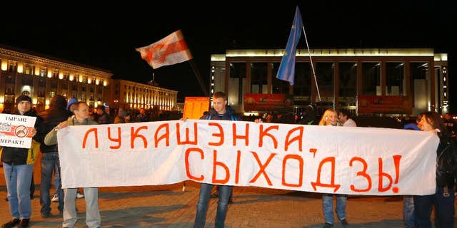 Belarusian opposition activists rally in the city center after presidential elections in Minsk, Belarus, late Sunday, Oct. 11, 2015. President Alexander Lukashenko was expected to win a fifth term in Sunday's election with ease, but he said anything much less than 80 percent of the vote would be a sign that his support was slipping. The authoritarian leader faced no serious competition in the election, which was boycotted by the opposition. The sign reads "Lukashenko, go away!" (AP Photo/Sergei Grits)