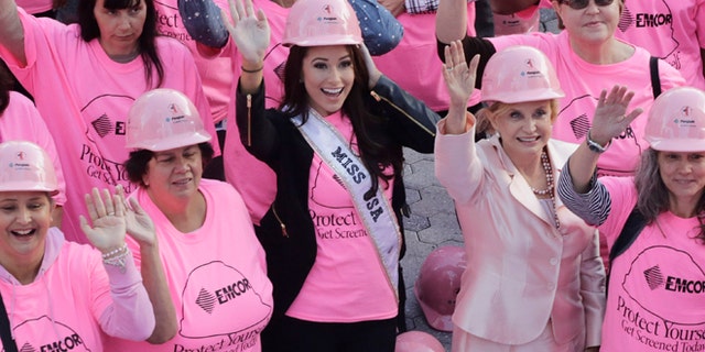 Nia Sanchez, center, Miss USA, joins hundreds of volunteers in pink hard hats and shirts to form a human pink ribbon in an event for Breast Cancer Awareness Month, Tuesday, Oct. 7, 2014 in New York. (AP Photo/Mark Lennihan)