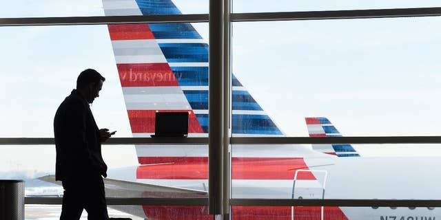 FILE - In this Jan. 25, 2016, file photo, a passenger talks on the phone as American Airlines jets sit parked at their gates at Washington's Ronald Reagan National Airport. American Airlines has agreed to pay $200 million for a stake in China Southern Airlines, the biggest of China's three major state-owned carriers, in a bid for a bigger share of the country's growing travel market. (AP Photo/Susan Walsh, File)