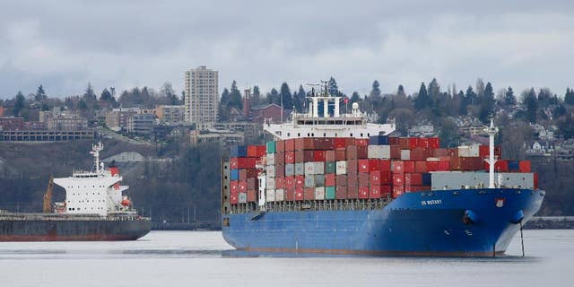 FILE - In this Feb. 20, 2015 file photo, the HS Mozart cargo ship, right, operated by the German shipping company Hansa Shipping, sits anchored in Commencement Bay near the Port of Tacoma, Wash. The Commerce Department reports on the U.S. trade gap for July on Thursday, Sept. 3, 2015. (AP Photo/Ted S. Warren, File)