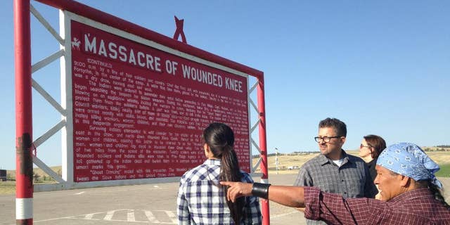 In this May 1, 2015 photo, Native American cartoonist Ricardo Cate', far right, and Chicano cartoonist Lalo Alcaraz, third right, visit Wounded Knee Memorial at Wounded Knee, S.D., on the Pine Ridge Indian Reservation. The nightclub attack in Orlando was initially described by some news organizations, including The Associated Press, as the deadliest mass shooting in U.S. history. In truth, America has seen even bigger massacres, some involving hundreds of men, women and children, like the one at Wounded Knee in 1890 against the Lakota. (AP Photo/Russell Contreras)