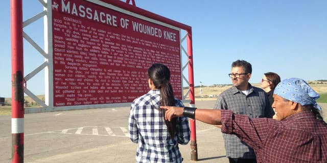 In this May 1, 2015 photo, Native American cartoonist Ricardo Cate', far right, and Chicano cartoonist Lalo Alcaraz, third right, visit Wounded Knee Memorial at Wounded Knee, S.D., on the Pine Ridge Indian Reservation. The nightclub attack in Orlando was initially described by some news organizations, including The Associated Press, as the deadliest mass shooting in U.S. history. In truth, America has seen even bigger massacres, some involving hundreds of men, women and children, like the one at Wounded Knee in 1890 against the Lakota. (AP Photo/Russell Contreras)