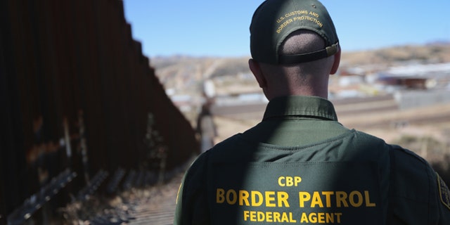 NOGALES, AZ - FEBRUARY 26: A U.S. Border Patrol agent looks along a section of the recently-constructed fence at the U.S.-Mexico border on February 26, 2013 in Nogales, Arizona. The new fencing, which ranges from 18-32 feet high in the Nogales area, allows Border Patrol agents to see through the fence and is harder for immigrants or drug smugglers to scale from the Mexican side. (Photo by John Moore/Getty Images)
