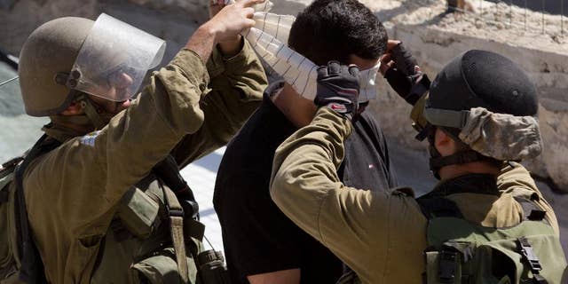 Israeli troops arrest a Palestinian during clashes after the funeral of Ibrahim Awad, 28, in the village of Beit Ummar near the West Bank city of Hebron, Thursday, Sunday, Oct. 11, 2015. Awad died of his wounds on Saturday after being shot by Israeli troops during a protest last week. (AP Photo/Majdi Mohammed)