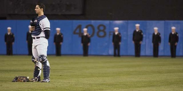 NEW YORK - OCTOBER 11: Yankees catcher Jorge Posada #20 stands in the outfield as a color guard displays a large American flag prior to Game two of the American League Divisional Series between the Oakland Athletics and the New York Yankees October 11, 2001 at Yankee Stadium in the Bronx, New York. The A's won 2-0. (Photo by M. David Leeds/Getty Images)