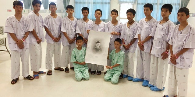 The rescued soccer team members pose with a sketch of the Thai Navy SEAL diver who died while trying to rescue them.
