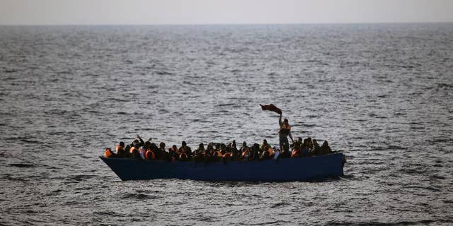 FILE- In this Friday, Feb. 3, 2017 file photo, migrants and refugees wave for help from inside a wooden boat 21 miles north of Sabratha, Libya. The chief of the European border and coast guard agency says migrant deaths in the Mediterranean on the Libya-to-Italy smuggling route have increased to a record level despite ever more rescue vessels trying to prevent mass drownings. (AP Photo/Emilio Morenatti, File)