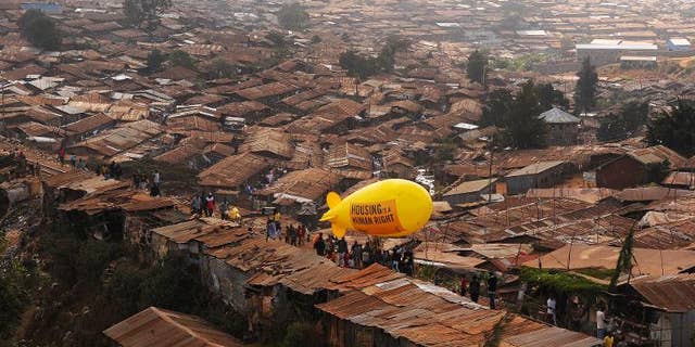Members of NGO Amnesty International carry a hot air balloon with text which reads 'Housing is a Human right' through the Kibera slum in Nairobi on March 24, 2012