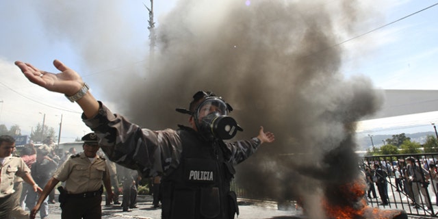 Sept. 30: A police officer demonstrates next to a bonfire during a protest of police officers and soldiers against a new law that cuts their benefits at a police base in Quito, Ecuador.