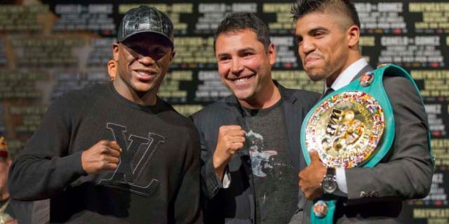 September 14, 2011: Floyd Mayweather, left, and Victor Ortiz, right, pose for a photo with Oscar De La Hoya after a news conference.