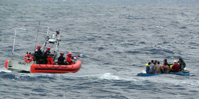 Coast Guard personnel left, try to assist a group of Cuban migrants on a makeshift vessel in the Florida Straits.