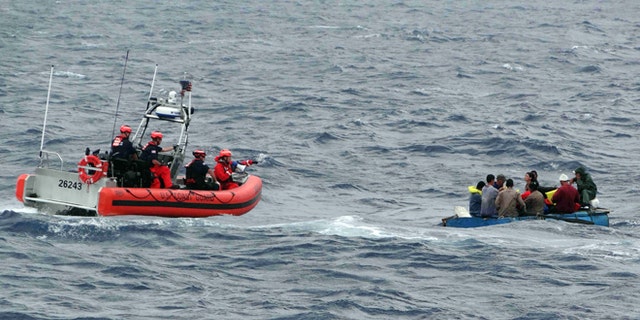 Coast Guard personnel left, try to assist a group of Cuban migrants on a makeshift vessel in the Florida Straits.